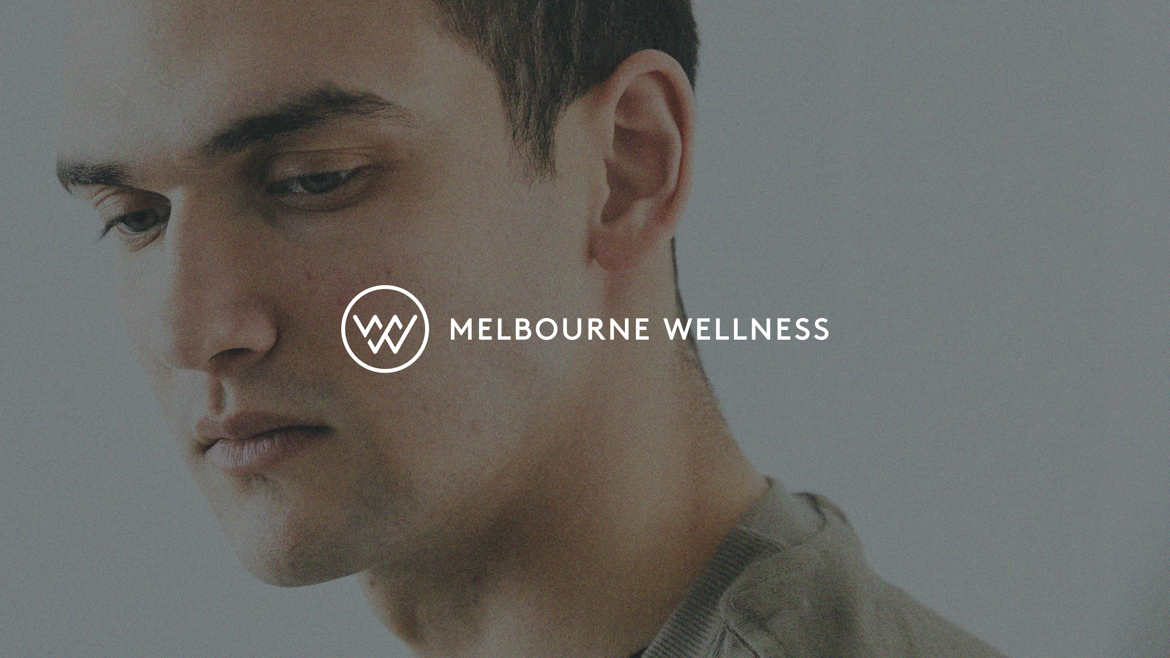 Melbourne Wellness wordmark logo lockup over lifestyle image of man looking downward